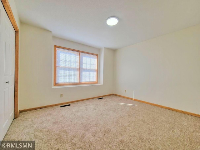 empty room featuring carpet, visible vents, and baseboards