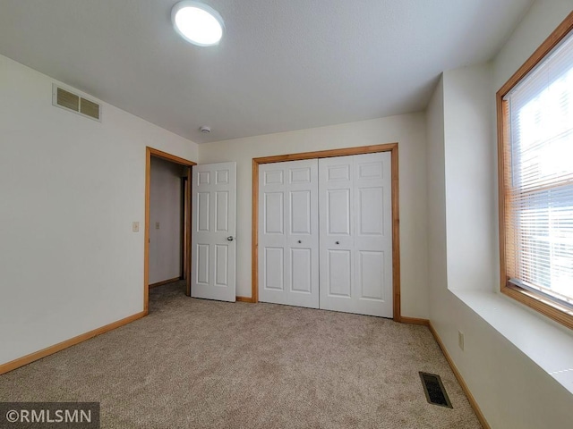 unfurnished bedroom featuring visible vents, baseboards, and carpet
