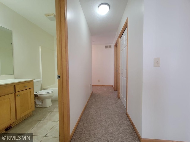 corridor with visible vents, baseboards, and light tile patterned flooring