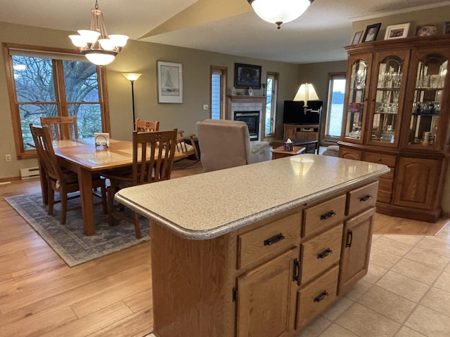 26837 Lake Ethel Rd, Girard Twp, MN 56515 - kitchen with a baseboard radiator, a glass covered fireplace, a center island, light countertops, and light wood-style flooring