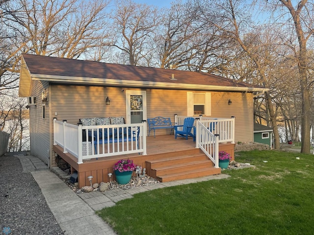 rear view of house featuring a wooden deck and a lawn