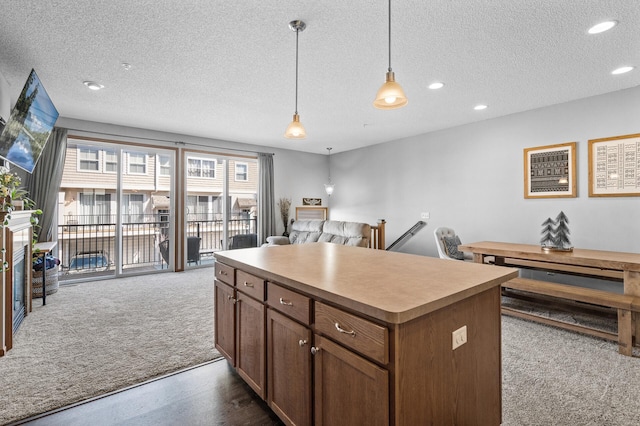 kitchen featuring dark carpet, a textured ceiling, a kitchen island, and open floor plan