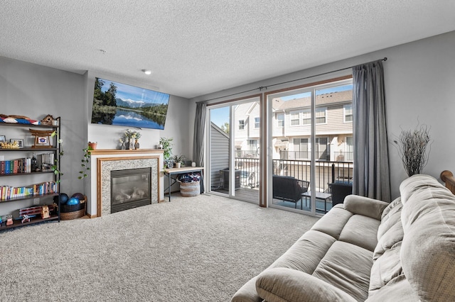 living area with a glass covered fireplace, carpet flooring, and a textured ceiling