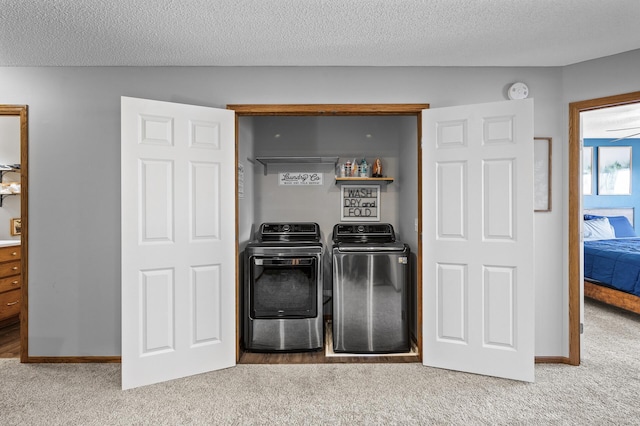 laundry room with washing machine and dryer, carpet flooring, a textured ceiling, and laundry area