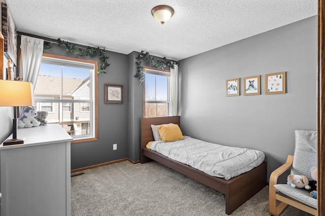 carpeted bedroom featuring a textured ceiling, baseboards, and multiple windows