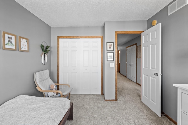 bedroom featuring a textured ceiling, a closet, visible vents, and light colored carpet