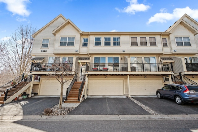 multi unit property with stairway, an attached garage, and driveway