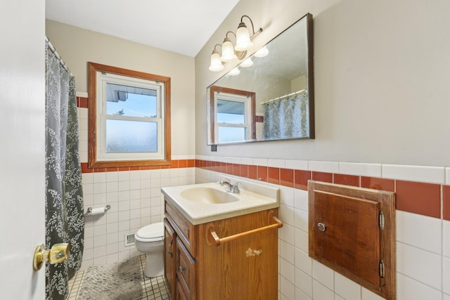 11749 Crooked Lake Blvd NW, Coon Rapids, MN 55433 - bathroom featuring tile walls, vanity, tile patterned floors, toilet, and wainscoting