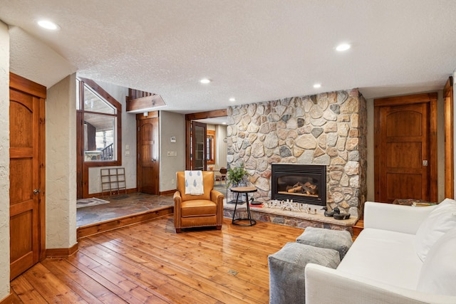 8434 Big Whitefish Narrows, Pine River, MN 56474 - living area with baseboards, a stone fireplace, recessed lighting, a textured ceiling, and hardwood / wood-style floors