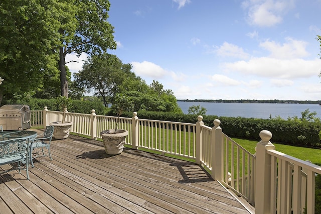 wooden deck featuring a lawn, a water view, and area for grilling