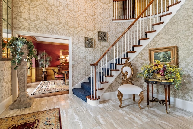 foyer entrance with wainscoting, stairway, and wallpapered walls