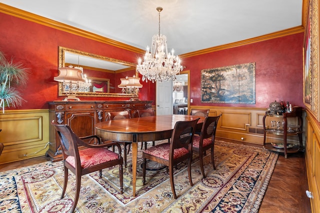 dining room featuring crown molding, wainscoting, a decorative wall, and a chandelier