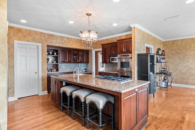 kitchen with a breakfast bar area, appliances with stainless steel finishes, baseboards, a notable chandelier, and light wood-style floors