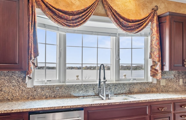 kitchen with reddish brown cabinets, a sink, dishwasher, and tasteful backsplash