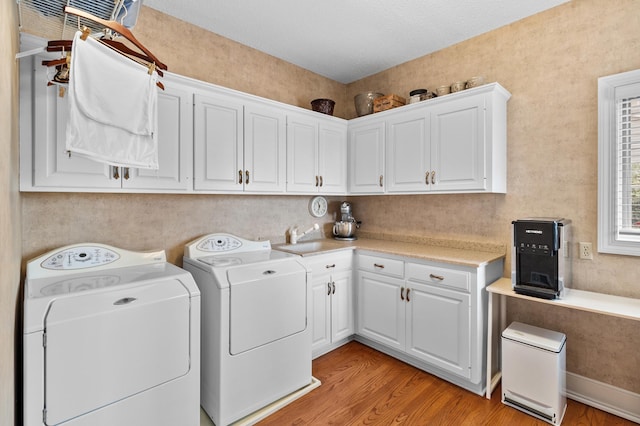 laundry room featuring cabinet space, a sink, washer and clothes dryer, and light wood finished floors