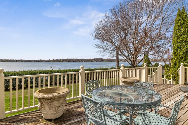 deck with a water view and outdoor dining space