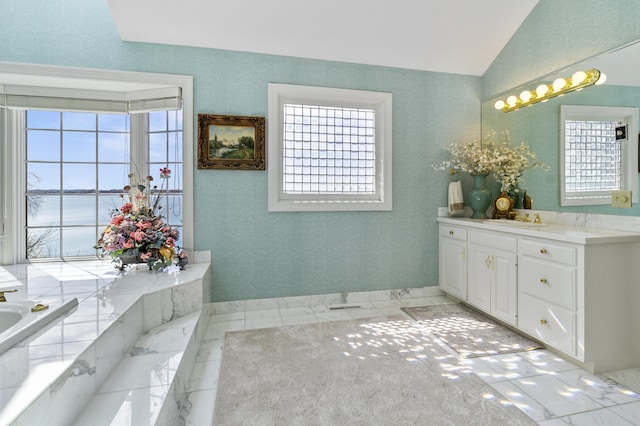 full bath with vanity, marble finish floor, a bathtub, and lofted ceiling