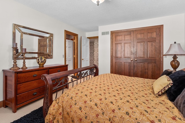 carpeted bedroom with a closet, a textured ceiling, and visible vents