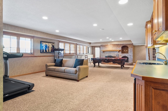living room with carpet floors, wallpapered walls, a brick fireplace, and recessed lighting
