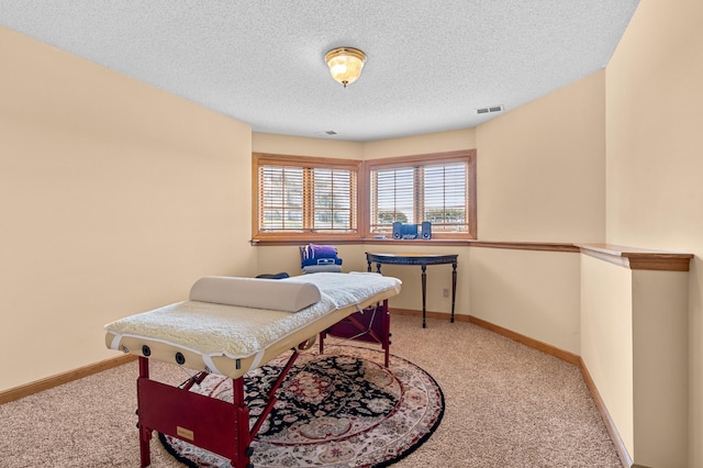 carpeted office space featuring visible vents, a textured ceiling, and baseboards