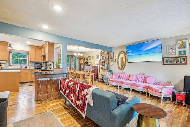 716 6th St NE, Minneapolis, MN 55413 - living room featuring a textured ceiling, light wood-style floors, a chandelier, and recessed lighting