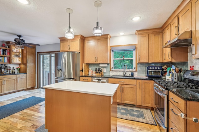 716 6th St NE, Minneapolis, MN 55413 - kitchen featuring stainless steel appliances, a sink, under cabinet range hood, a kitchen island, and light wood finished floors