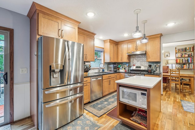 716 6th St NE, Minneapolis, MN 55413 - kitchen with appliances with stainless steel finishes, under cabinet range hood, backsplash, hanging light fixtures, and light wood-style flooring