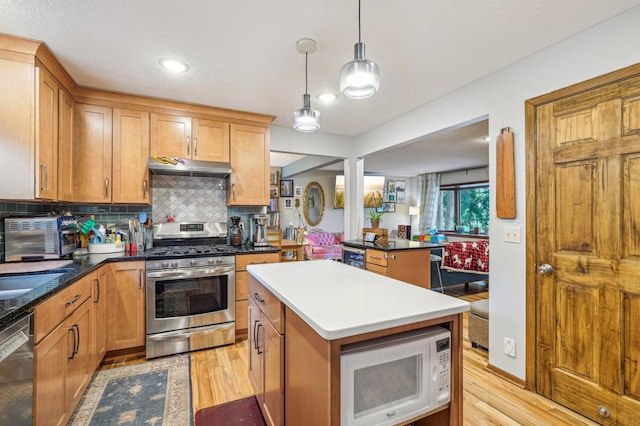 716 6th St NE, Minneapolis, MN 55413 - kitchen with stainless steel appliances, under cabinet range hood, light wood finished floors, and tasteful backsplash
