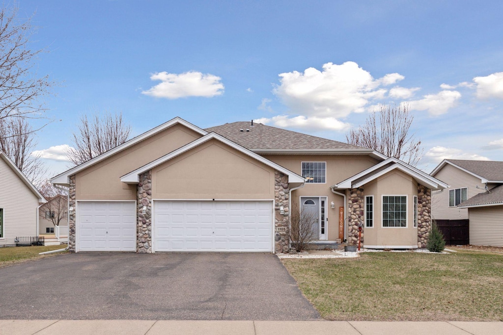 view of front of property with aphalt driveway, stucco siding, stone siding, a front lawn, and a garage