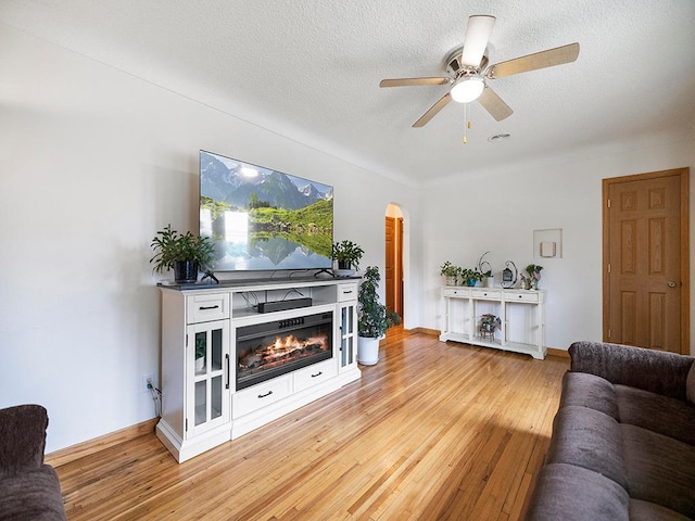 1883 County Road C E, Maplewood, MN 55109 - living area featuring light wood-type flooring, ceiling fan, a glass covered fireplace, a textured ceiling, and arched walkways