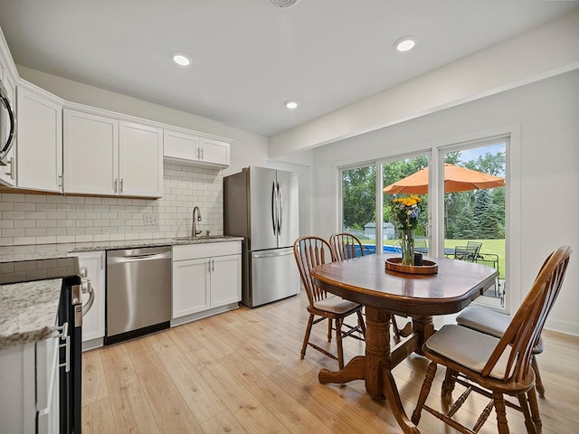 1883 County Road C E, Maplewood, MN 55109 - kitchen with appliances with stainless steel finishes, white cabinets, tasteful backsplash, light stone counters, and recessed lighting