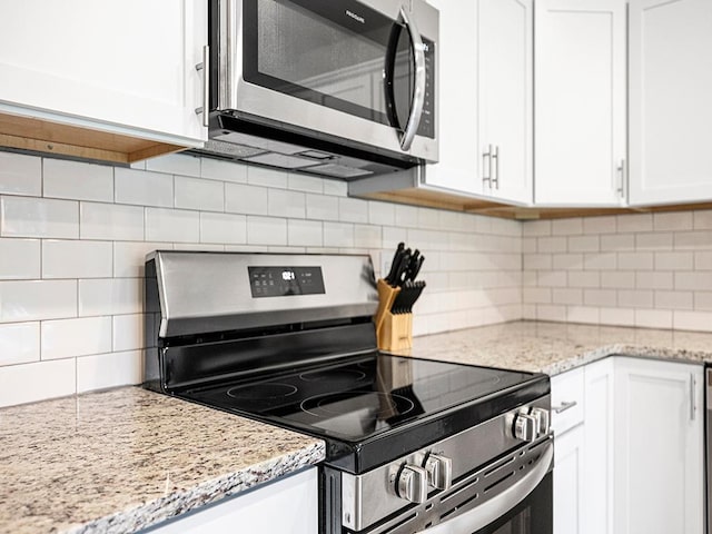 1883 County Road C E, Maplewood, MN 55109 - kitchen featuring stainless steel appliances, white cabinetry, tasteful backsplash, and light stone countertops