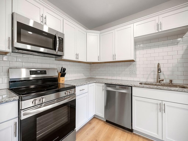 1883 County Road C E, Maplewood, MN 55109 - kitchen featuring stainless steel appliances, white cabinets, tasteful backsplash, light wood-style flooring, and light stone countertops