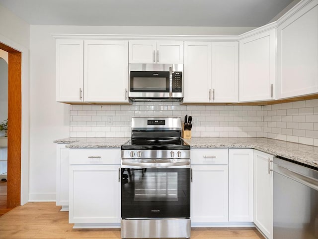 1883 County Road C E, Maplewood, MN 55109 - kitchen with appliances with stainless steel finishes, light wood-type flooring, backsplash, light stone countertops, and white cabinets