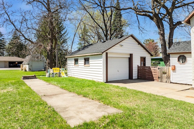 detached garage featuring driveway, fence, and a gate