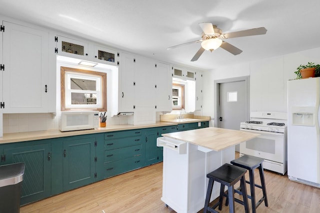 kitchen featuring white appliances, a kitchen breakfast bar, light wood-type flooring, ceiling fan, and backsplash