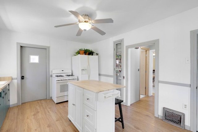 kitchen with a ceiling fan, white appliances, light wood finished floors, visible vents, and a kitchen breakfast bar