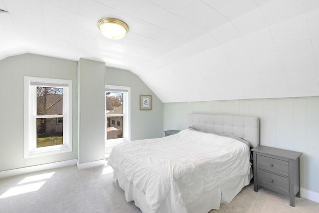 bedroom featuring vaulted ceiling, light colored carpet, and baseboards
