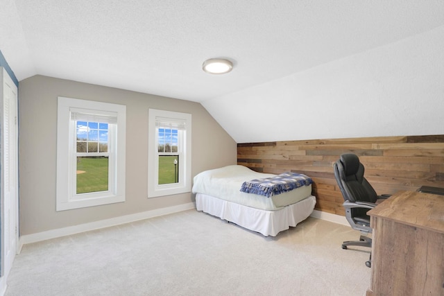 bedroom with wooden walls, vaulted ceiling, baseboards, and light carpet