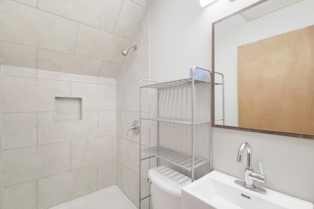 bathroom with a sink, toilet, and tiled shower