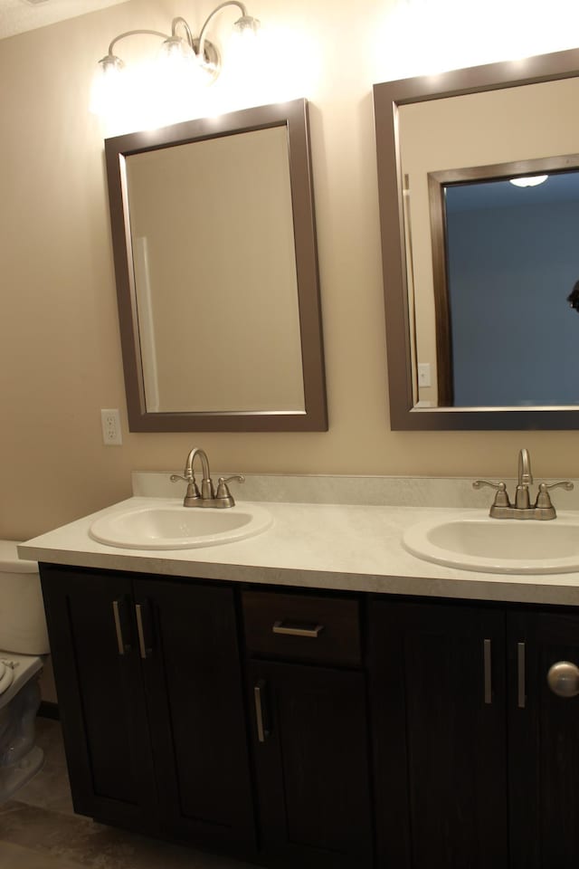 bathroom with toilet, double vanity, and a sink