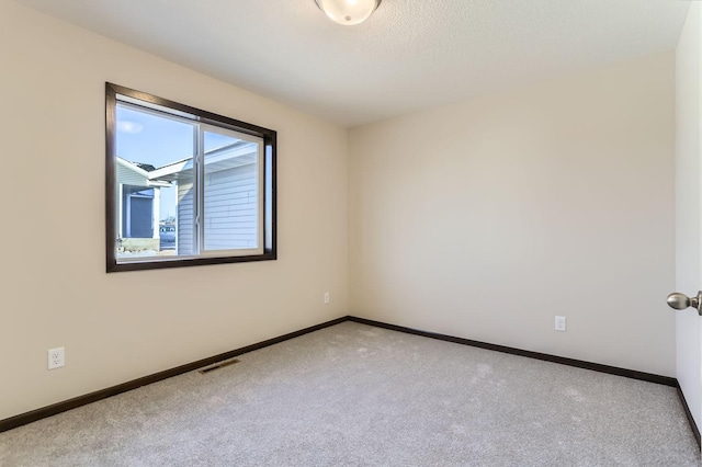 empty room featuring visible vents, baseboards, and carpet