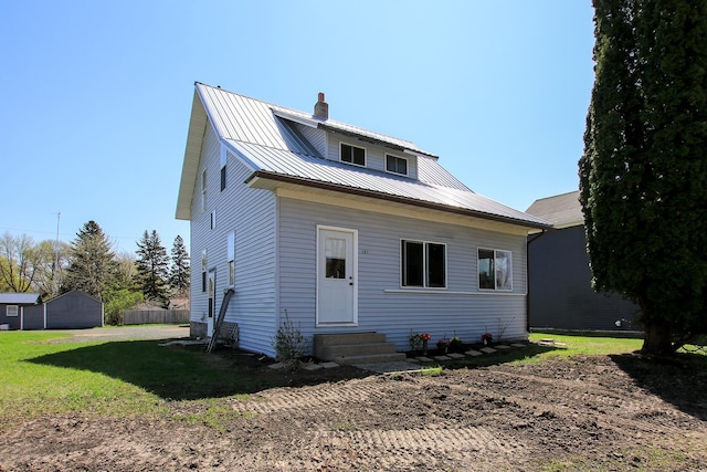 bungalow-style home featuring metal roof, entry steps, a chimney, and a front yard