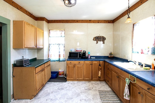 kitchen featuring dark countertops, pendant lighting, and a sink