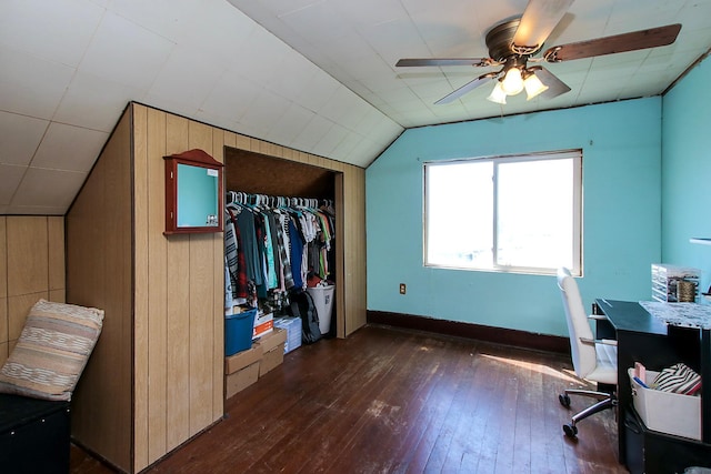 interior space featuring lofted ceiling, a closet, dark wood-type flooring, and wood walls