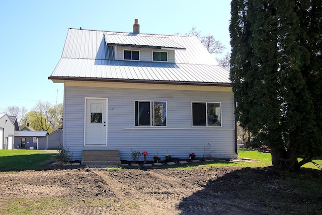 rear view of property featuring metal roof, a chimney, and entry steps