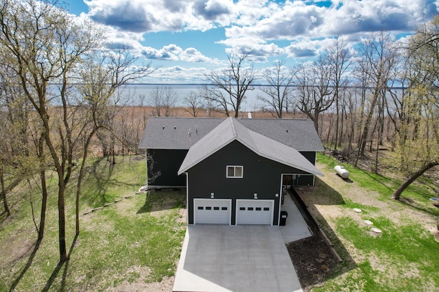 36861 477th Ave, Otto Twp, MN 56567 - view of side of property with concrete driveway, an attached garage, roof with shingles, and a yard