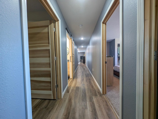 36861 477th Ave, Otto Twp, MN 56567 - corridor with wood finished floors, a textured wall, baseboards, and a barn door