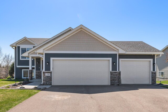 craftsman inspired home featuring a garage, driveway, roof with shingles, and stone siding