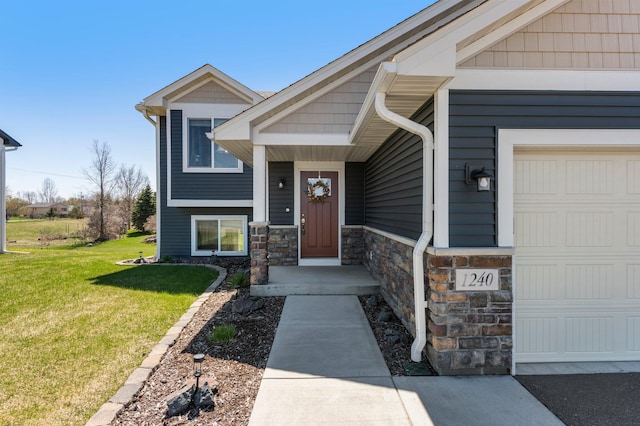 entrance to property featuring a garage, a yard, and stone siding